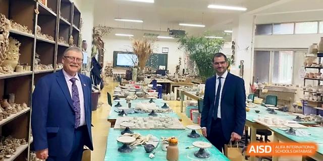 A man in a suit stands in a large art or craft room filled with various student projects and materials at WeiFang No.1 Middle School.