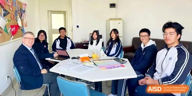 Students in blue and white tracksuits sit around a hexagonal table for a collaborative group study session at WeiFang No.1 Middle School.