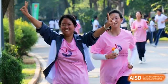 Two female students wearing pink event t-shirts smile and pose for the camera during a charity run at WeiFang No.1 Middle School.