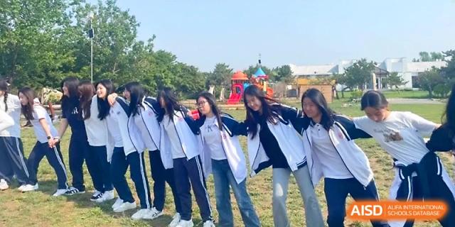 A group of female students in blue and white jackets pose together with their arms around each other at WeiFang No.1 Middle School.