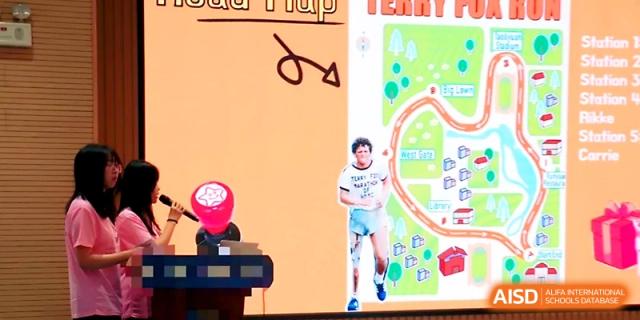 Two students in pink shirts stand at a podium giving a presentation with a "Road Map" slide behind them at WeiFang No.1 Middle School.
