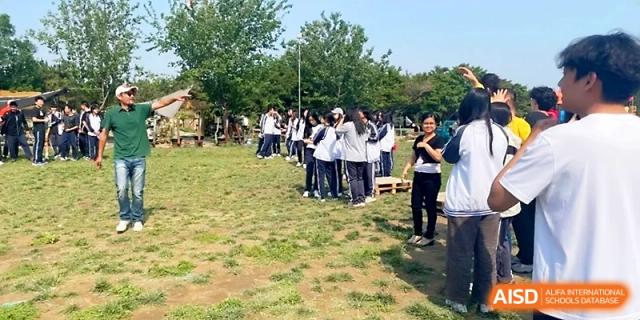 A large group of students gathers in a grassy field for an outdoor activity or assembly under a clear sky at WeiFang No.1 Middle School.