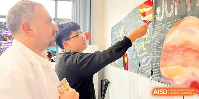 A student interacts with an educational display board, pointing out specific details during a project presentation at Wuhan No.2 High School.