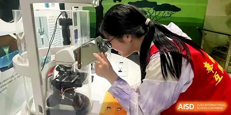 A student looks through a microscope in a well-equipped science laboratory during a biology research session at Wuhan No.2 High School.
