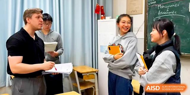 Students and a teacher share a laugh during an informal classroom discussion, highlighting the friendly atmosphere at Wuhan No.2 High School.