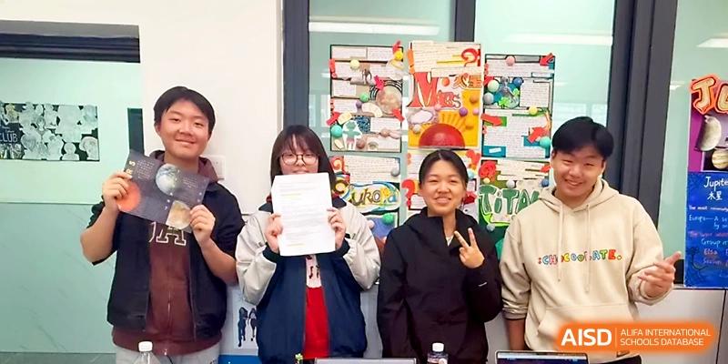 Three happy students pose together while holding up a certificate of achievement after a successful project at Wuhan No.2 High School.