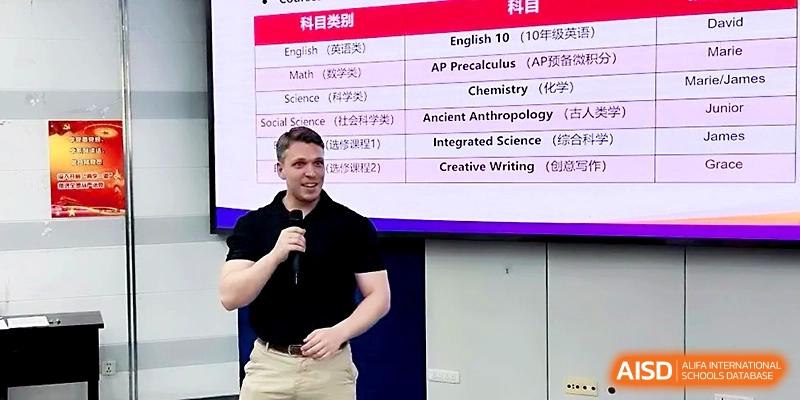 A male instructor presents a course curriculum table on a large screen during an orientation meeting at Wuhan No.2 High School.