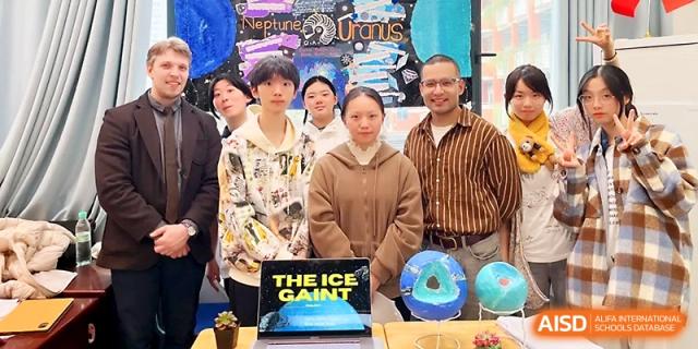 A group of students and teachers pose together in front of a creative "Ice Giant" space-themed project at Wuhan No.2 High School.