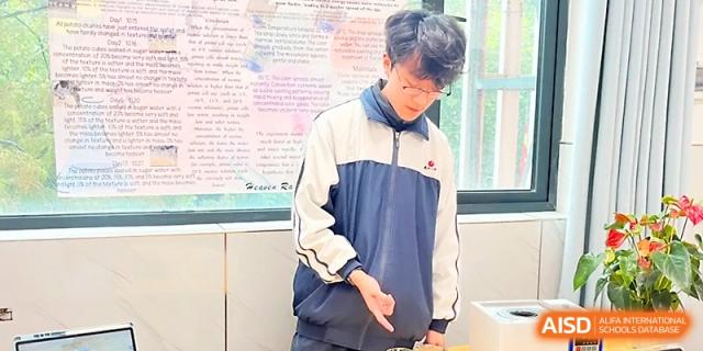 A male student in a school jacket stands thoughtfully in a classroom during a lesson at Wuhan No.2 High School.