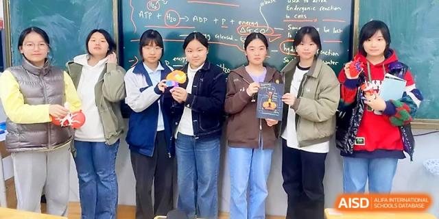 Four female students pose together while holding small crafts and awards at Wuhan No.2 High School.