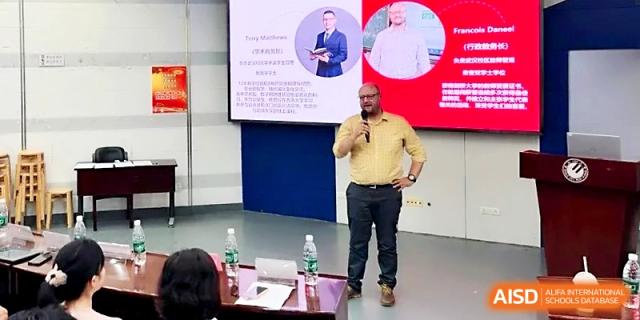 A male instructor gives a presentation in front of a digital screen in a lecture hall at Wuhan No.2 High School.