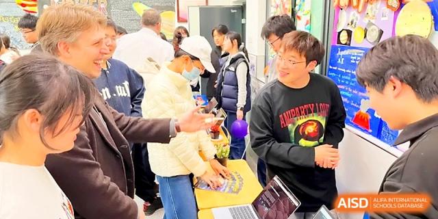 Students gather around a table to participate in a hands-on technical workshop at Wuhan No.2 High School.
