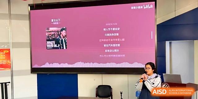 A large digital screen displays a presentation for an audience in a darkened hall at Wuhan No.2 High School.