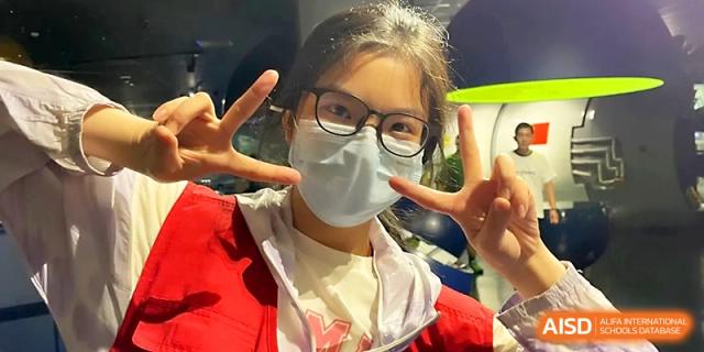 A smiling student wearing a mask and glasses gives a peace sign to the camera at Wuhan No.2 High School.