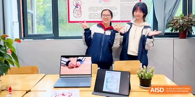 Two students pose proudly with their laptops and digital projects on display at Wuhan No.2 High School.
