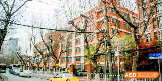 A scenic view of the multi-story brick school building framed by lush green trees at Wuhan No.2 High School.