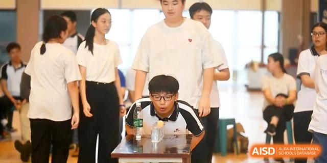 Students compete in a fun relay game involving blowing a ball across water cups at Wuhan No.2 High School.