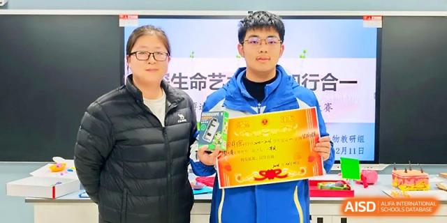 A student proudly holds a large red and gold award certificate next to a teacher in a classroom at Xi_an Bodi School.