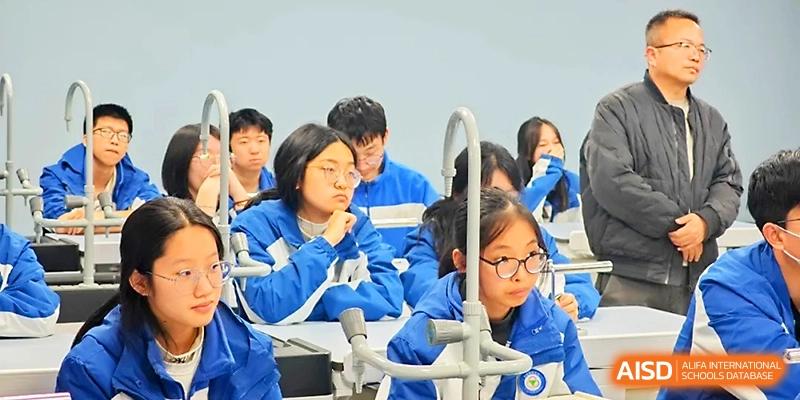 Students wearing glasses and blue school uniforms focus intently on a science lesson in a lab setting at Xi_an Bodi School.