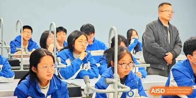 Students wearing glasses and blue school uniforms focus intently on a science lesson in a lab setting at Xi_an Bodi School.