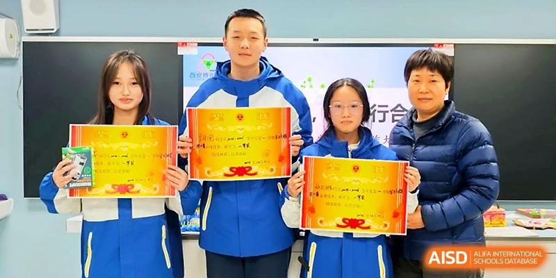 Three students stand together displaying their official academic achievement certificates in front of a screen at Xi_an Bodi School.