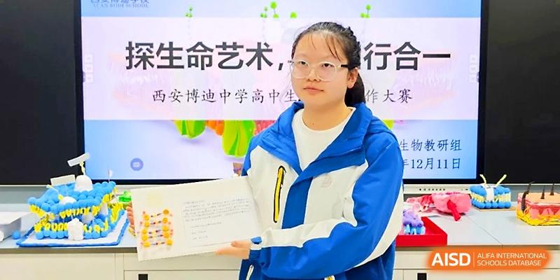 A student presents a handmade educational project and book during a biology or science fair at Xi_an Bodi School.
