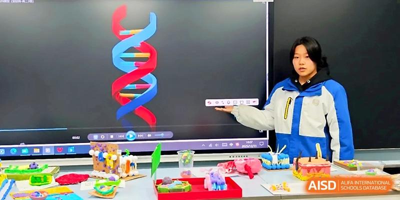 A student points toward a digital screen displaying a 3D DNA double helix model during a science presentation at Xi_an Bodi School.
