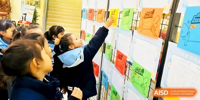 A young girl reaches up to organize colorful papers on a vertical display rack in a classroom at Xi_an Bodi School.