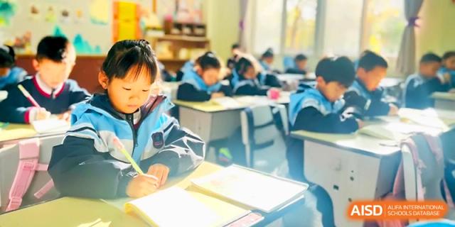 A classroom of young children is seen studying and writing carefully in their workbooks at Xi_an Bodi School.