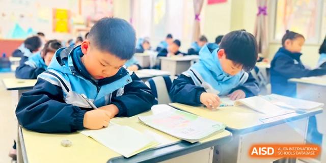 Two young students sit at their desks while working diligently on their school assignments at Xi_an Bodi School.