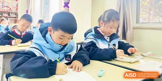 A boy and girl work side-by-side on their lessons in a bright and modern classroom environment at Xi_an Bodi School.
