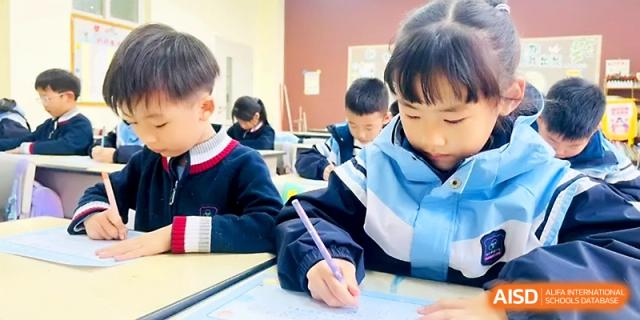 Primary school students sit together at desks while practicing their handwriting in class at Xi_an Bodi School.