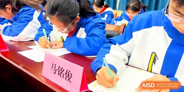 A student focuses on their work at a desk during a school-wide academic or creative competition at Xi_an Bodi School.