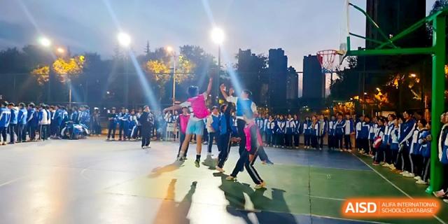 Students compete in a basketball game under stadium lights during an outdoor sports competition at Xi_an Bodi School.