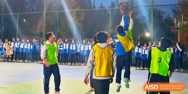 Two students jump high to reach for a basketball during an outdoor physical education class at Xi_an Bodi School.