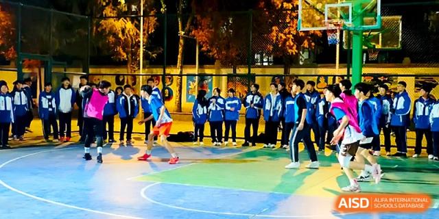 A student prepares to serve or play during a sports match while teammates watch from the side at Xi_an Bodi School.