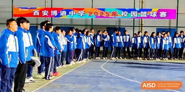 A long row of students in blue uniforms stands in formation on the outdoor sports court at Xi_an Bodi School.