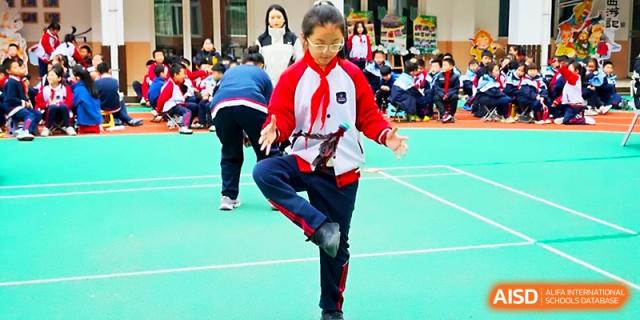 A young student in a red and white tracksuit practices a physical activity on the outdoor court at Xi_an Bodi School.