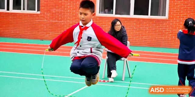 A young student jumps high while practicing jump rope during an outdoor physical education class at Xi_an Bodi School.