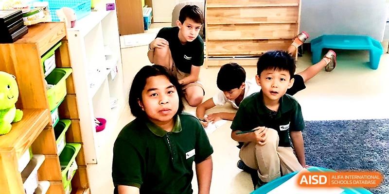 Three young boys sit on the floor of a classroom while working on a collaborative group project at Xi_an Hanova International School.