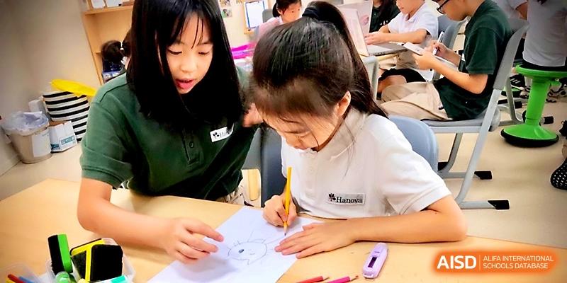 Two young girls work closely together on a drawing at a desk during an art or design class at Xi_an Hanova International School.
