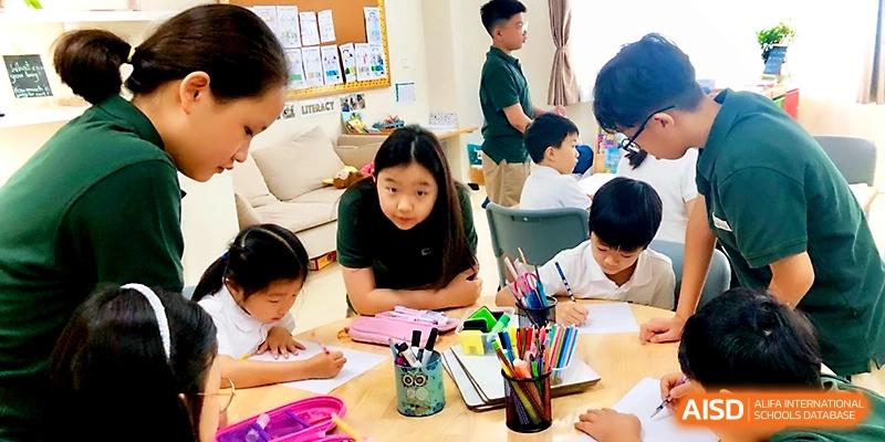 A group of students sits at a classroom table filled with colorful pens and notebooks for a study session at Xi_an Hanova International School.