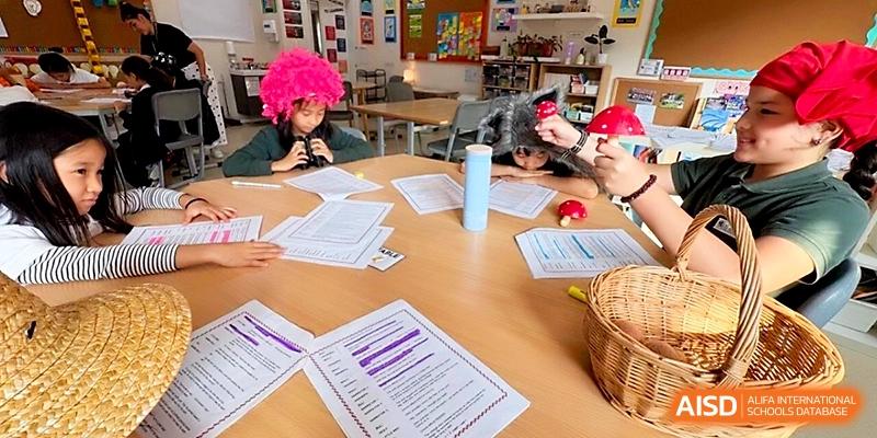 Students participate in a creative classroom activity involving papers and colorful accessories at a round table at Xi_an Hanova International School.