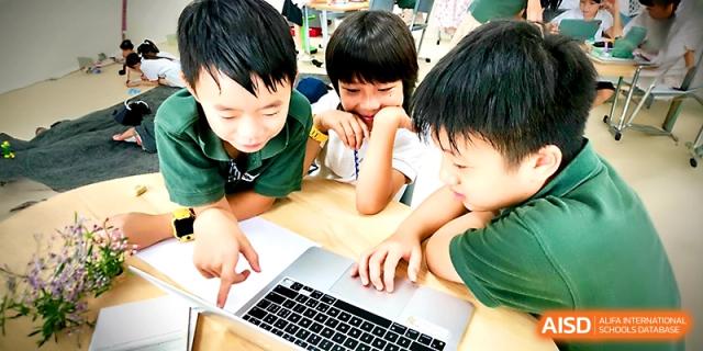 Three students gather around a laptop to work on a digital assignment or research project together at Xi_an Hanova International School.