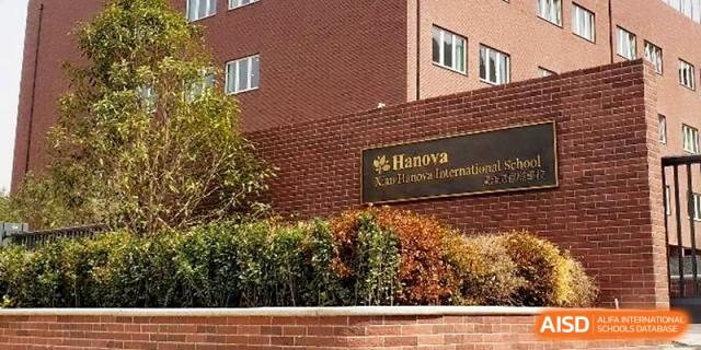 A view of the red brick exterior of the primary school building featuring a gold school sign at Xi_an Hanova International School.