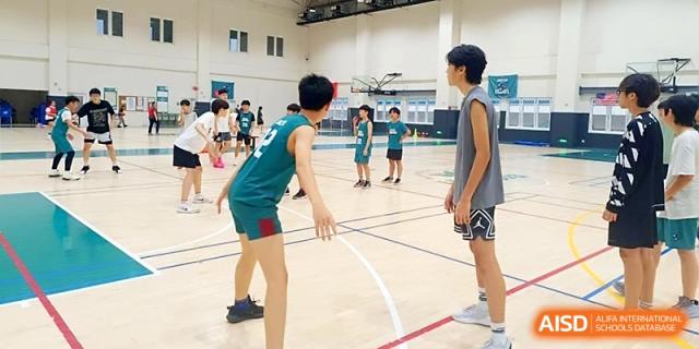 Students practice basketball drills and teamwork on an indoor court during a sports session at Xi_an Hanova International School.