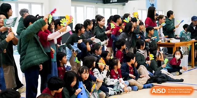 A large group of students gathers excitedly for an outdoor school assembly or cultural event at Xi_an Hanova International School.