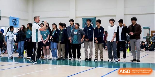 Students and staff stand together on a basketball court during a formal sports or cultural assembly at Xi_an Hanova International School.