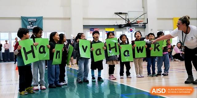 Students hold up green and white letters to spell out "HANOVA" during a school spirit event at Xi_an Hanova International School.