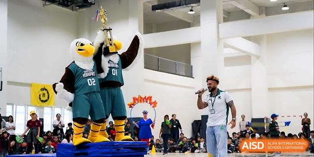 A school mascot and a presenter engage with the audience during a high-energy school celebration at Xi_an Hanova International School.